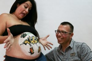 mujer embarazada mostrando a su marido su barriga pintada con belly painting